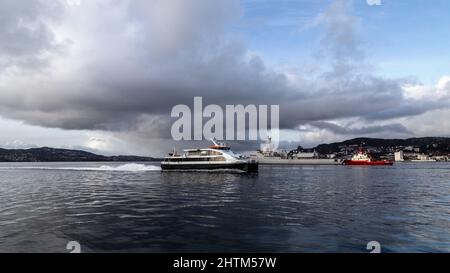 Catamaran local à grande vitesse Ekspressen à Byfjorden, à la sortie du port de Bergen, en Norvège. En passant devant une frégate hollandaise, et remorqueur de bateau BB wor Banque D'Images