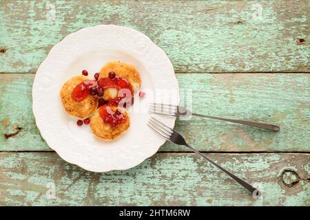 Syrniki, crêpes russes au fromage cottage avec confiture de framboise pour le petit déjeuner vue sur la tête Banque D'Images