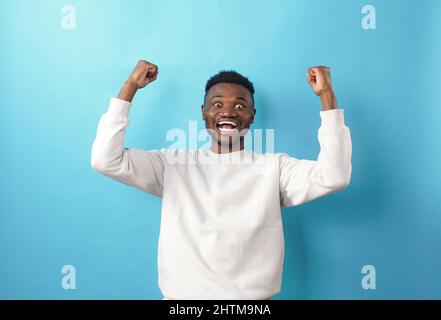 Portrait d'un jeune Africain américain joyeux criant avec ses mains soulevées dans un signe de succès Banque D'Images