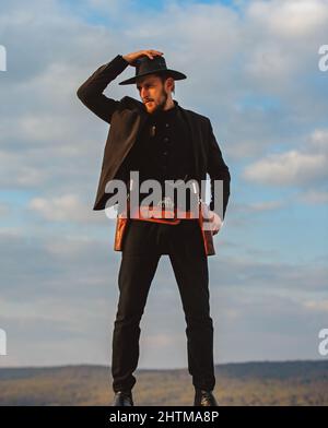 Shérif ou cowboy en costume noir et chapeau de cowboy.Homme avec pistolet revolver West vintage et munitions marshales.Ouest américain, shérif. Banque D'Images