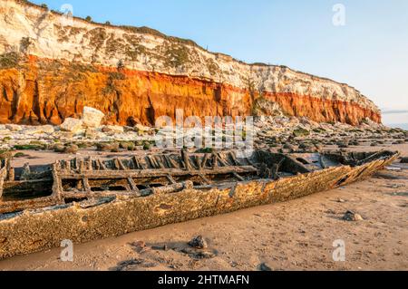 L'épave du Sheraton du chalutier à vapeur sous les falaises rayées rouges et blanches de Hunstanton à marée basse. Banque D'Images