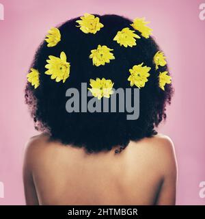 Aussi naturel qu'il devient. Photo en vue arrière d'une femme debout avec des fleurs dans ses cheveux. Banque D'Images