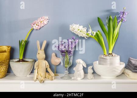 Jacinthe blanche dans un grand bol en porcelaine, figurines de lièvres et un oiseau, sont sur la cheminée contre le mur bleu foncé. Mise en page. Concept de ressort Banque D'Images