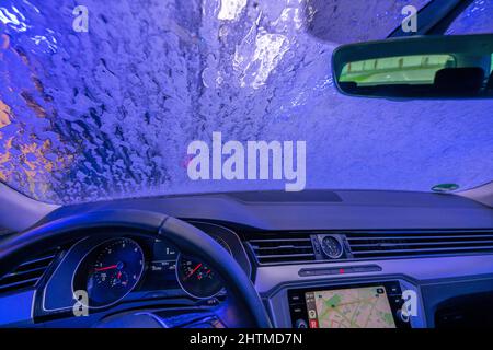 Voiture dans un lavage automatique de voiture, ligne de lavage de voiture, la mousse de nettoyage est vaporisée, brosses rotatives nettoyer le véhicule, Banque D'Images