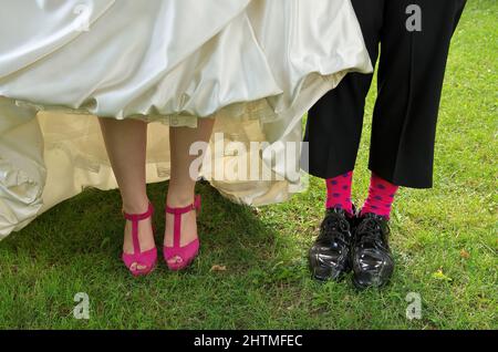 Gros plan sur les talons et les chaussettes de mariée et de marié Funky rose Banque D'Images