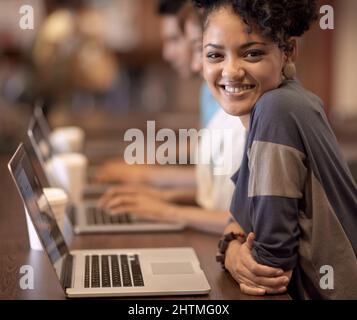 Vers un avenir radieux. Groupe d'étudiants utilisant un ordinateur portable pour effectuer une affectation de groupe. Banque D'Images
