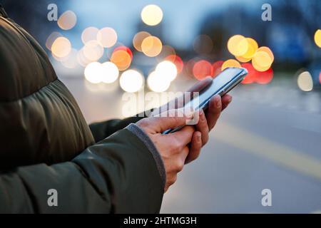 Gros plan des mains d'une femme utilisant un smartphone la nuit dans la rue, la recherche ou le concept de réseau social, Banque D'Images