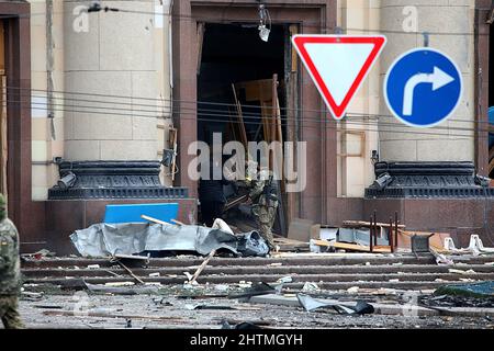 Les hommes ramassent les débris lors de l'effort de réponse à l'abattage des envahisseurs russes devant le bâtiment de l'Administration régionale de l'État de Kharkiv, sur la place Svobody (liberté), le mardi 1 mars, à Kharkiv, dans le nord-est de l'Ukraine. Banque D'Images