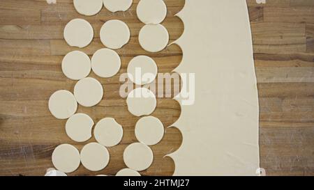 Pâte à pain plate ronde pour boulettes. Scène. Vue de dessus gros plan des mains faisant de la pâte ronde avec de la farine sur une table. Concept de cuisine maison. Banque D'Images