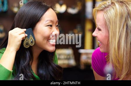 Les vrais amis donnent des conseils de mode honnêtes. Une jeune femme asiatique demande à son ami une opinion sur une paire de boucles d'oreilles. Banque D'Images