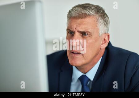 Quoi. Photo d'un homme d'affaires mature qui semble frustré en travaillant sur son ordinateur au bureau. Banque D'Images