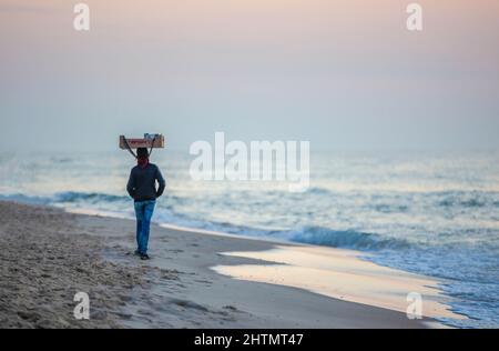 Gaza, Palestine. 01st mars 2022. Un vendeur palestinien marche sur la plage méditerranéenne au coucher du soleil dans la ville de Gaza. (Photo de Yousef Masoud/SOPA Images/Sipa USA) crédit: SIPA USA/Alay Live News Banque D'Images