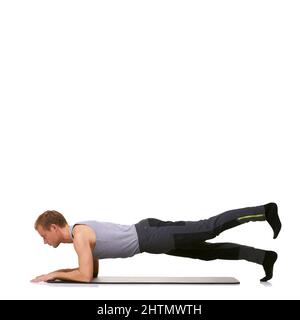 Perfectionner sa technique. Un jeune homme en forme effectuant une routine d'exercice tout en étant isolé sur un fond blanc. Banque D'Images