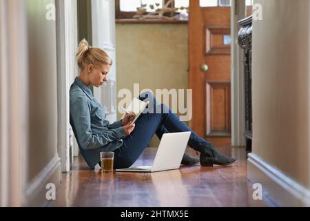 En vous privant de pensées. Une jeune femme assise sur le sol fait des recherches sur son ordinateur portable. Banque D'Images