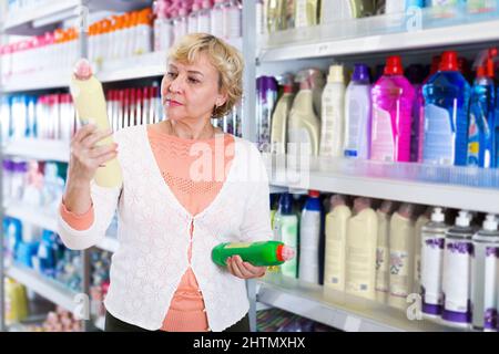 Femme choisissant des produits pour le nettoyage de la maison dans la boutique Banque D'Images