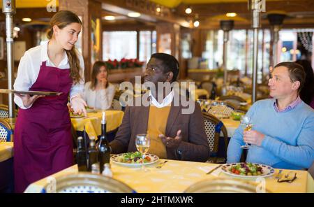 Deux hommes commandant la nourriture et parlant avec la serveuse au restaurant Banque D'Images
