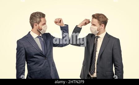les hommes d'affaires en masque se cognent les coudes au lieu de serrer les mains pour éviter le contact, salutation d'affaires. Banque D'Images