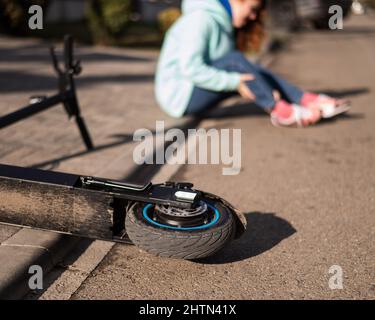 Une femme de race blanche est tombée d'un scooter électrique et a blessé sa jambe.Souffrant de douleur. Banque D'Images