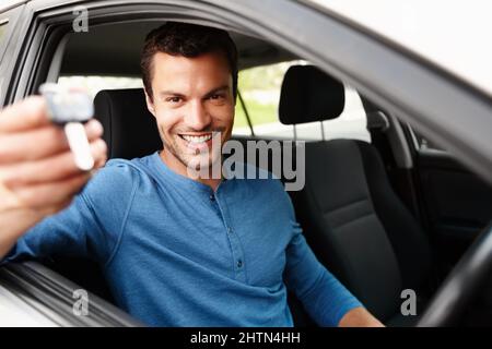 Fier propriétaire d'une nouvelle voiture. Homme souriant assis dans sa voiture en tenant les clés de sa voiture. Banque D'Images