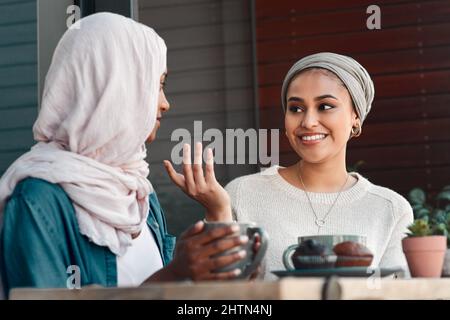 Ils ont beaucoup à parler. Photo courte de deux jeunes amies affectueuses qui ont une discussion dans un café tout en étant vêtues de hijab. Banque D'Images