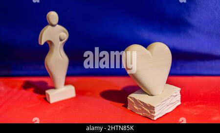 Agadir, Maroc - 20 février 2022 : statues amazigh en pierre blanche sculpture de l'amour, sur table rouge avec fond en soie bleue Banque D'Images