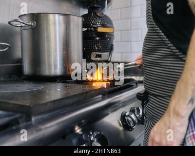 Faire cuire à l'aide de pinces pour enlever le charbon de bois qui est sur le feu dans un restaurant Banque D'Images