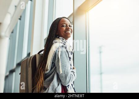 Ce sera ma première fois de vol. Photo courte d'une jeune femme regardant par la fenêtre de l'aéroport en attendant le départ. Banque D'Images