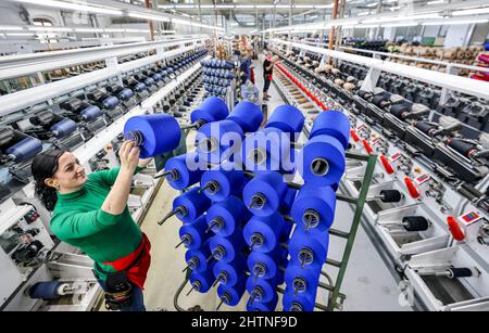 01 mars 2022, Saxe, Flöha: Deux employés changent de bobines avec des fils de couleur dans le département de bobinage d'OTEX Textilveredlung GmbH. La société, qui emploie 90 personnes, produit des fils spéciaux pour les produits médicaux et les textiles techniques. Lorsqu'un successeur a été recherché pour l'usine en 2016, Bauerfeind AG, un fabricant de matériel médical comme les bandages, les orthèses ou les semelles intérieures orthopédiques, de Thuringe, a simplement repris son fournisseur lui-même. Le nombre d'employés a augmenté, et maintenant plusieurs Roumains et Sud-Américains font également partie de la main-d'œuvre. Le mercredi (02.03.2022), l'Association de l'EAS Banque D'Images