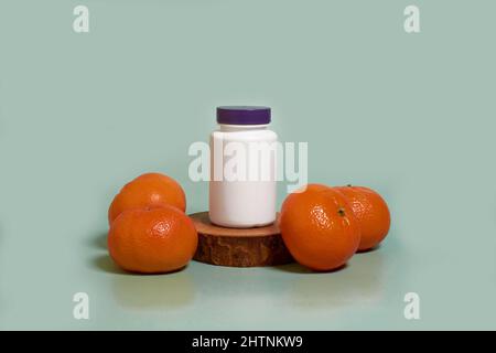Maquette. Un pot en plastique blanc avec un couvercle violet sur un support en bois et des mandarines Banque D'Images