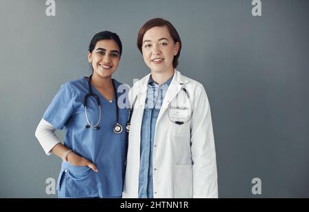 Votre santé est de la plus haute importance. Prise de vue de deux jeunes travailleurs de la santé dans un hôpital sur fond gris. Banque D'Images