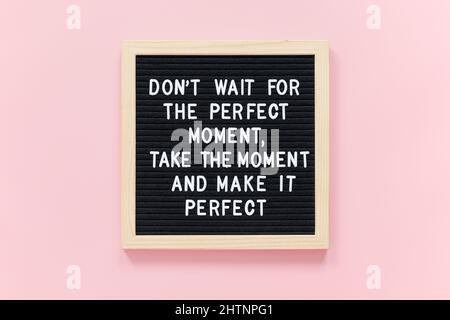 N'attendez pas le moment parfait, prenez le moment et rendez-le parfait. Citation motivationnelle sur un cadre de tableau de lettres noir sur fond rose. Concept INS Banque D'Images