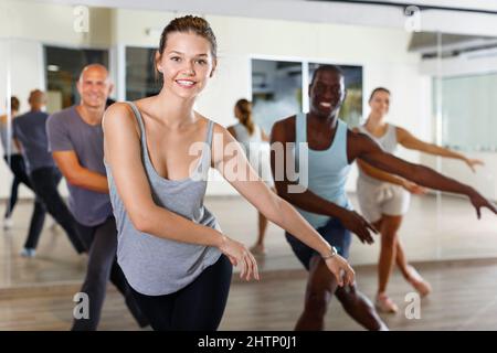 Des gens joyeux pratiquant des mouvements de sauts lindy vigoureux en classe de danse Banque D'Images