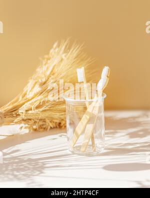 Bain spa composition d'un ensemble familial de trois brosses à dents écologiques en bois et bambou dans un pot en verre sur fond beige. Concept de zéro déchet, n Banque D'Images