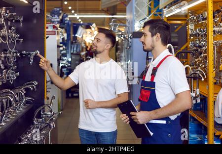 Assistant commercial dans un magasin de matériel aidant un client à choisir un robinet pour son évier de cuisine Banque D'Images