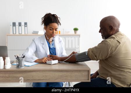 Femme noire médecin vérifiant la pression de mesure sur la main du patient Banque D'Images