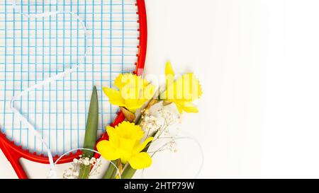 Tennis. Composition sport de vacances avec raquette de tennis avec bouquet de jonquilles sur fond blanc avec espace copie. Le sport et un mode de vie sain. Le Banque D'Images