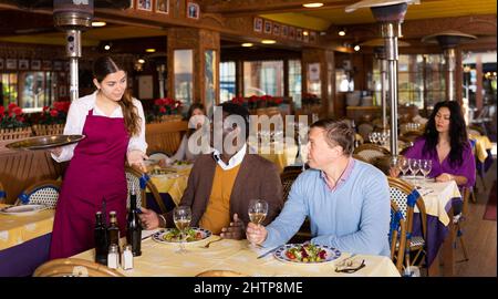 Deux hommes commandant la nourriture et parlant avec la serveuse au restaurant Banque D'Images