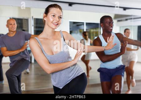 Des gens joyeux pratiquant des mouvements de sauts lindy vigoureux en classe de danse Banque D'Images