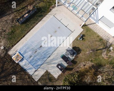 Un drone survolait une piscine couverte avec une bâche encore en construction dans un jardin Banque D'Images