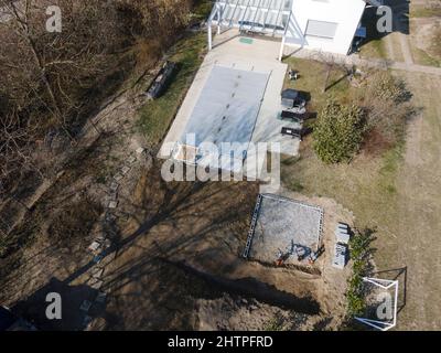 Un drone survolait une piscine couverte avec une bâche encore en construction dans un jardin Banque D'Images