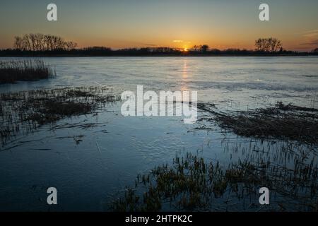 Vue en soirée sur un lac glacé au coucher du soleil, Stankow, Pologne Banque D'Images