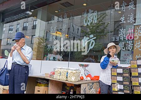 Une scène de rue dans Chinatown, Flushing où deux étrangers ont leur déjeuner. À Queens, New York. Banque D'Images