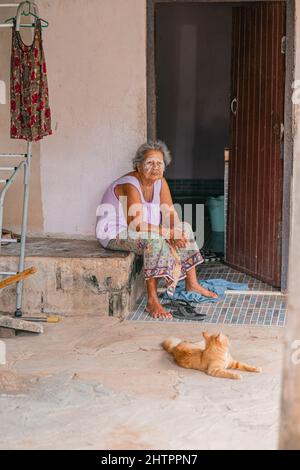 Vieille femme avec de la pâte de thanaka sur son visage assis près de la porte de sa maison Thaïlande Banque D'Images
