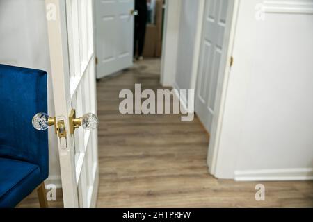 porte ouverte sur le couloir avec murs blancs et sol luxueux en bois naturel Banque D'Images