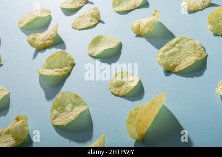 Photo plein format de pommes de terre croustilles disposées sur fond bleu avec ombre Banque D'Images