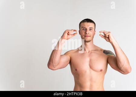 L'huile de poisson est mangée par un homme dans les mains de flacons et un verre bouteille huile santé, traitement des oméga pharmaceutique foie mode de vie, jeune morue Banque D'Images