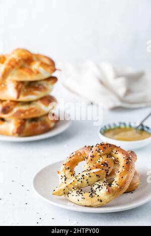 Une portion d'un bretzel cuit servi avec une sauce à la moutarde et une pile à l'arrière. Banque D'Images