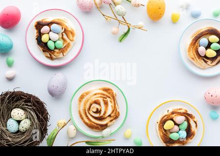 Nids de meringue faits maison remplis de mini œufs de chocolat pour Pâques. Banque D'Images