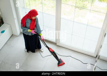 Bonne femme musulmane nettoyage moderne de la maison salon. Photo de haute qualité Banque D'Images