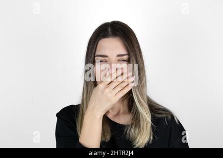 Une femme mécontente couvre le nez avec la main, sent quelque chose d'horrible, pince le nez, fronces les sourcils dans le mécontentement, voit pile de déchets, vêtu de vêtements décontractés, Banque D'Images